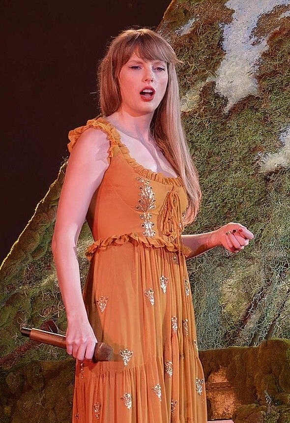 Taylor Swift performing in a gold dress during the Eras Tour in Arlington, Texas, in April 2023.