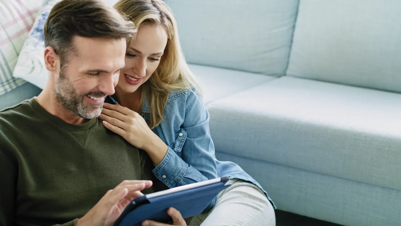 A couple sitting close together and looking at a tablet